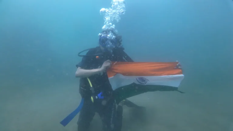 Diver holds out an Indian flag underwater as a stream of bubbles rises above