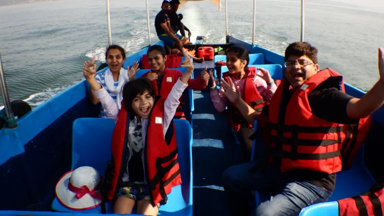 Family in red life jackets cheer and wave from the seats of a blue boat out at sea