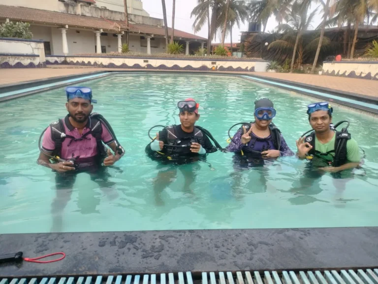Four beginners in full scuba gear in the training pool before their first sea dive