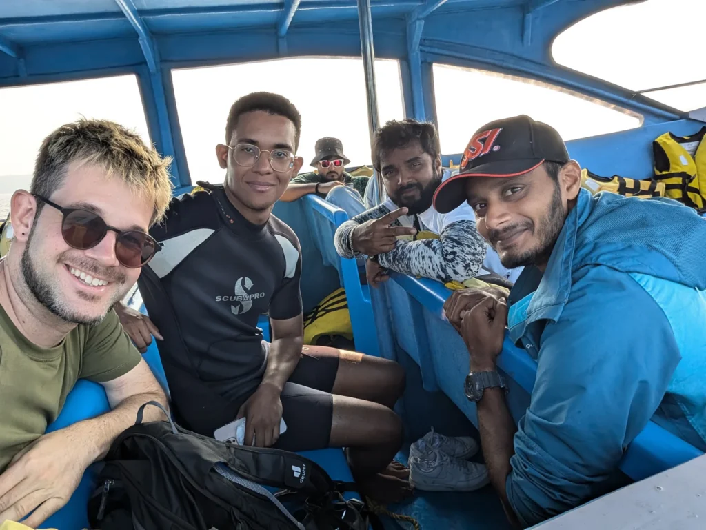 Group of smiling divers seated on the dive boat, one in a Scubapro wetsuit