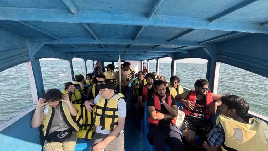 Boat full of guests in yellow life jackets heading out to sea
