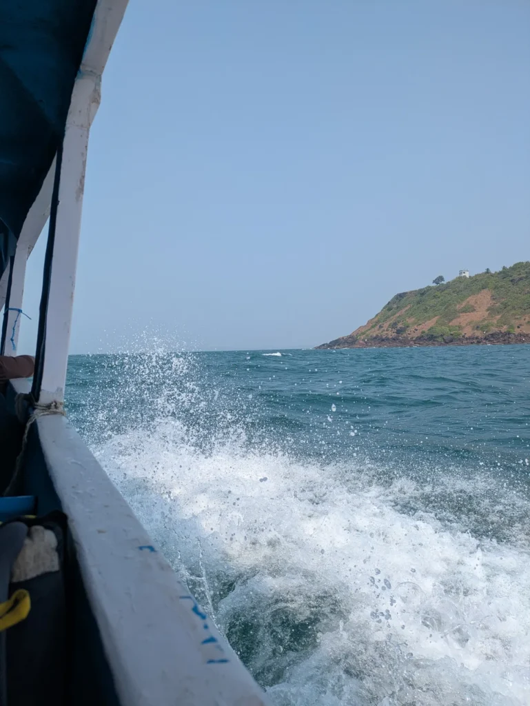 Spray off the side of a speeding boat heading toward a green headland