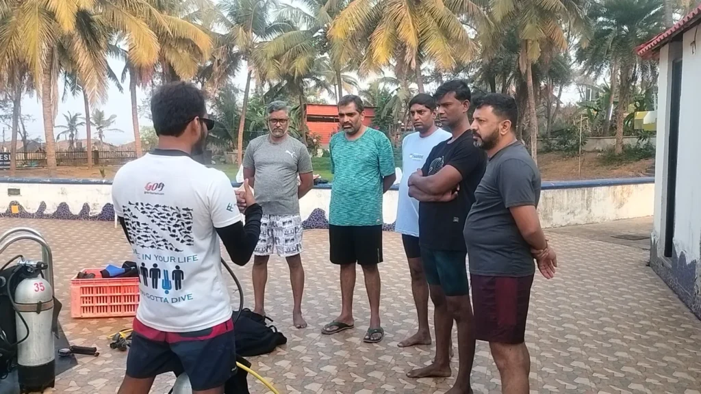 Instructor briefing a group of five men on a pool deck before training