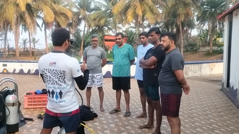 Instructor briefing a group of five men on a pool deck before training