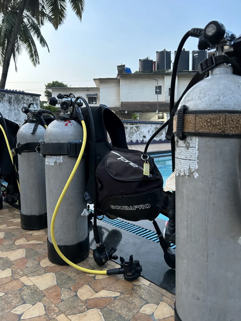 Scuba tanks with a Scubapro BCD and regulators lined up poolside