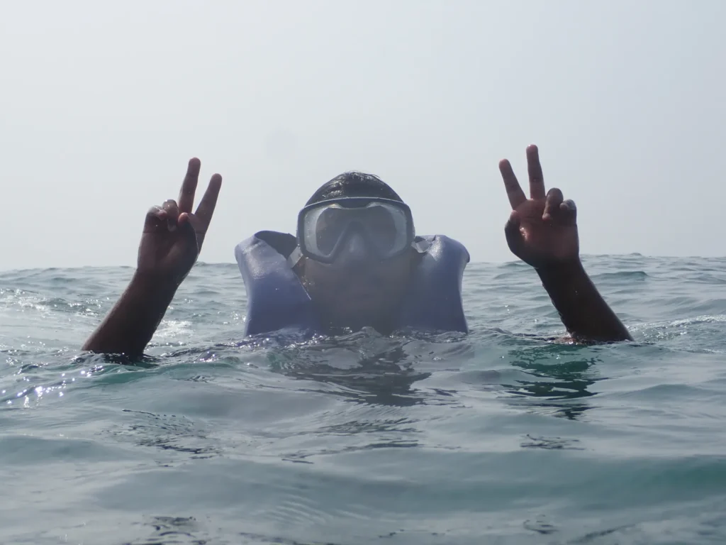 Snorkeler in a life jacket making peace signs at the sea surface