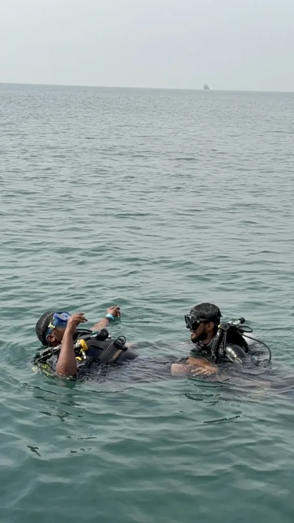 Instructor and student in scuba gear talking at the open-sea surface