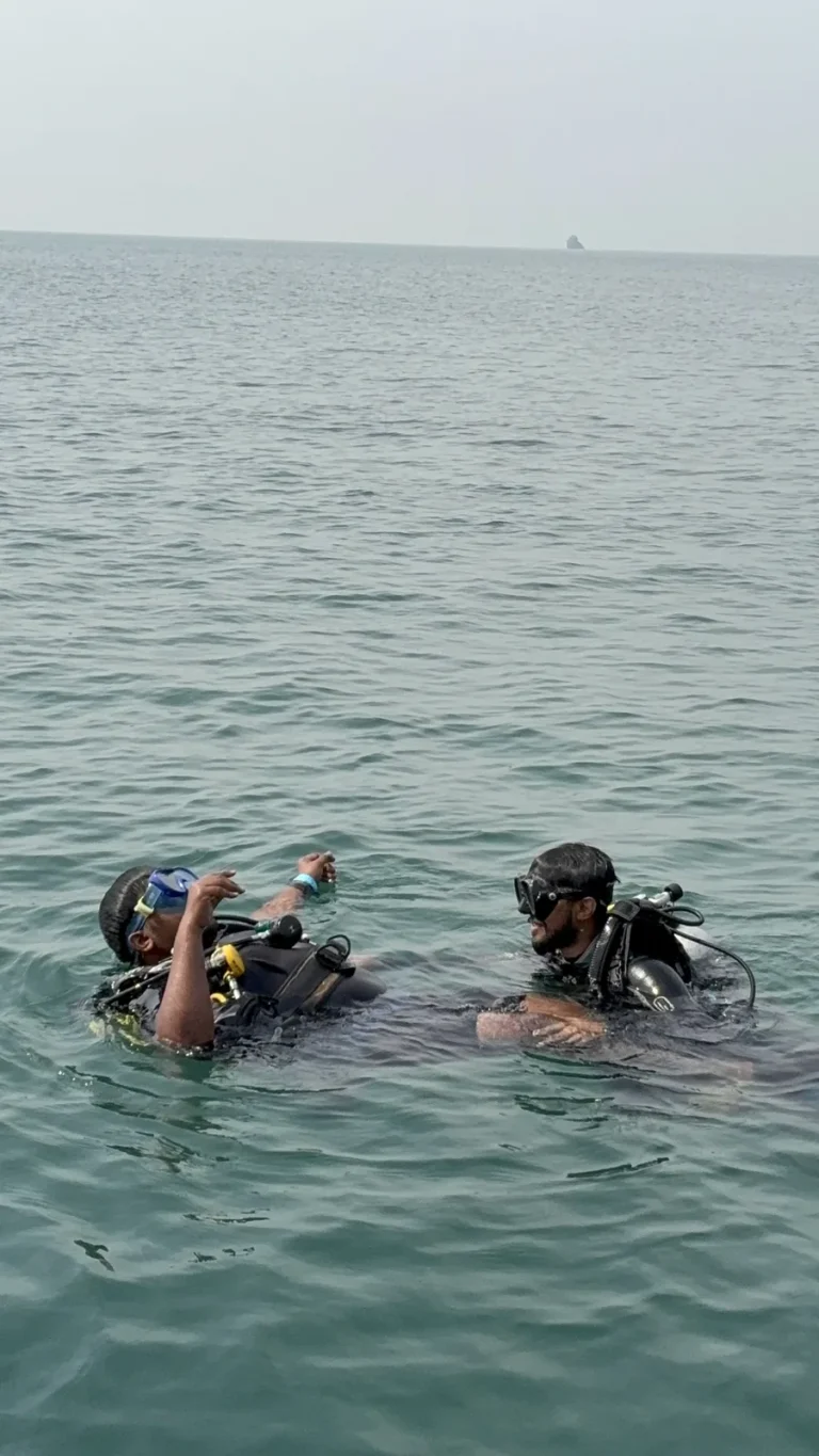 Instructor and student in scuba gear talking at the open-sea surface