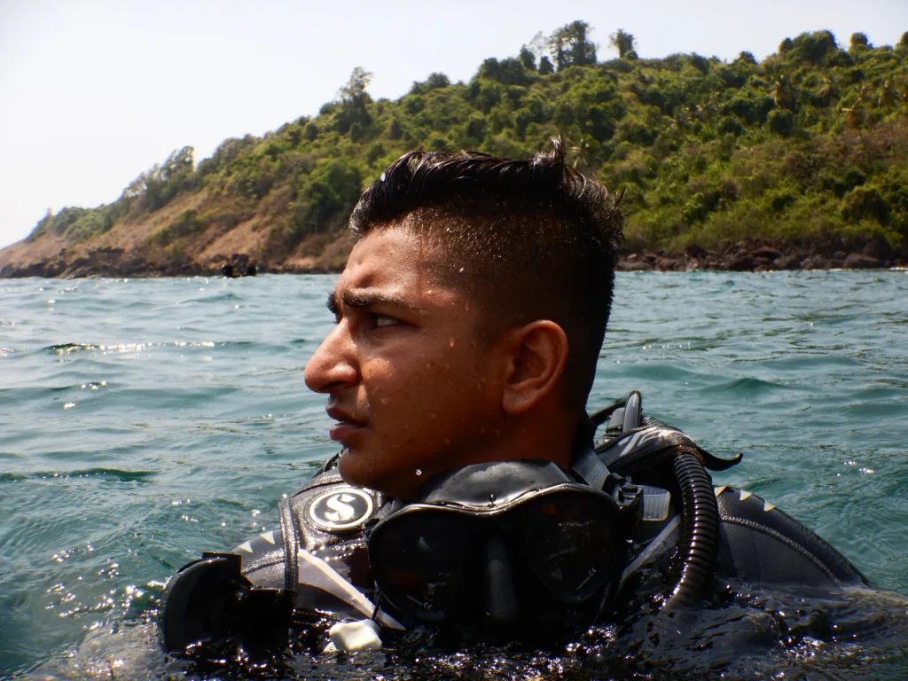Diver in a Scubapro BCD at the sea surface with a green island coastline behind