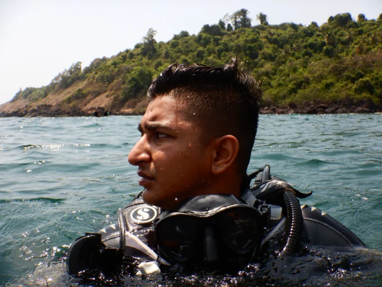 Diver in a Scubapro BCD at the sea surface with a green island coastline behind