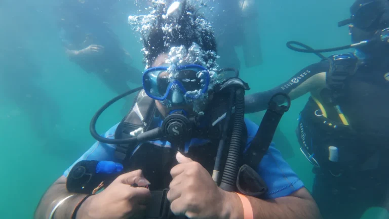 Diver with bubbles rising over his head while an instructor holds him underwater