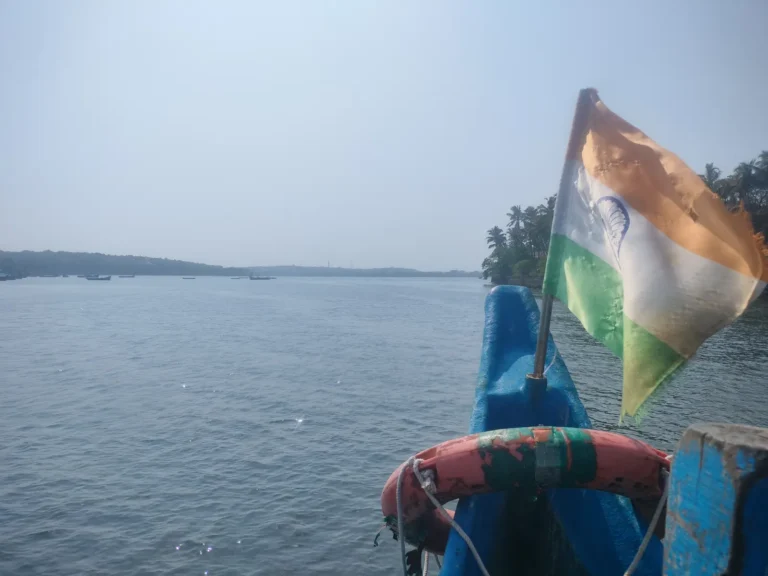 Indian flag and a life ring on the bow of a boat looking across a wide, hazy bay