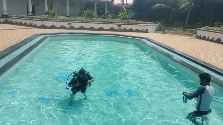 Student in full gear stands in the resort pool while an instructor holds a camera nearby