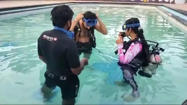 Instructor checking a beginner's mask during pool training in Candolim
