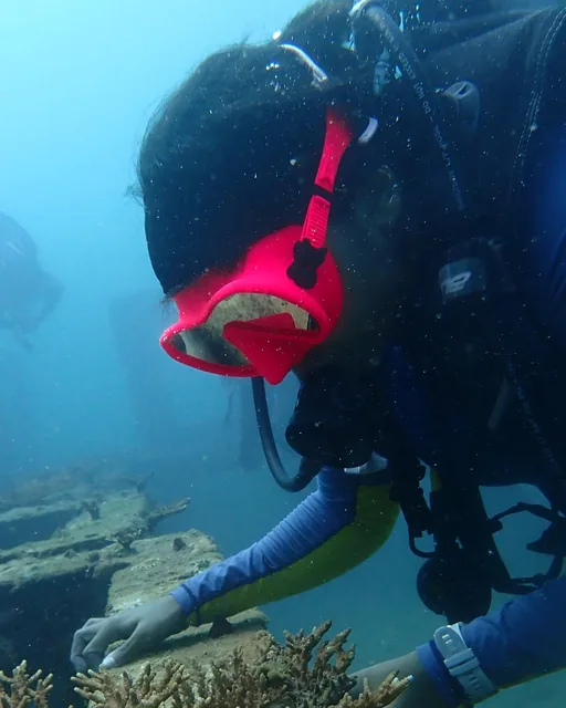 Trishala, Divemaster and freediver at FlyingFish Scuba School, checking coral on an underwater cleanup dive